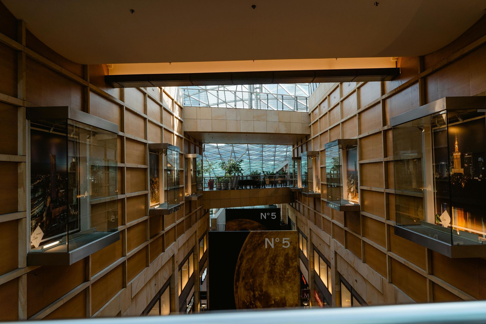 Interior of a mall with display cases on the walls. A glass ceiling lets light in, illuminating the space.