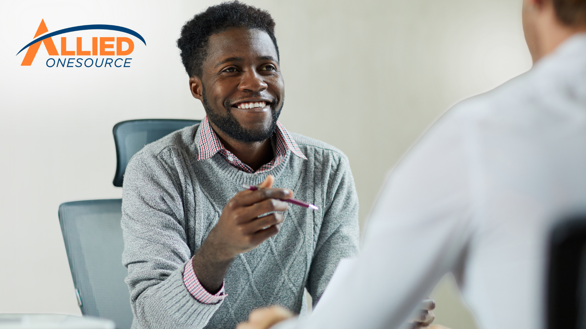 A smiling professional discusses remote work opportunities during a meeting with a recruiter.