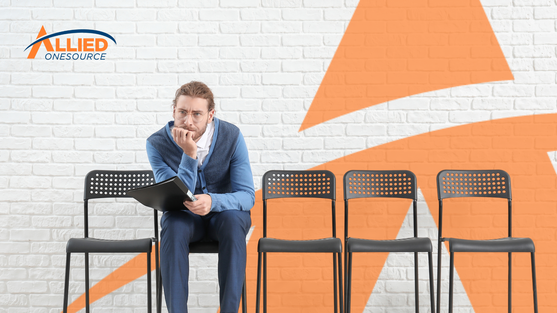 A man sitting on a chair in front of four chairs.