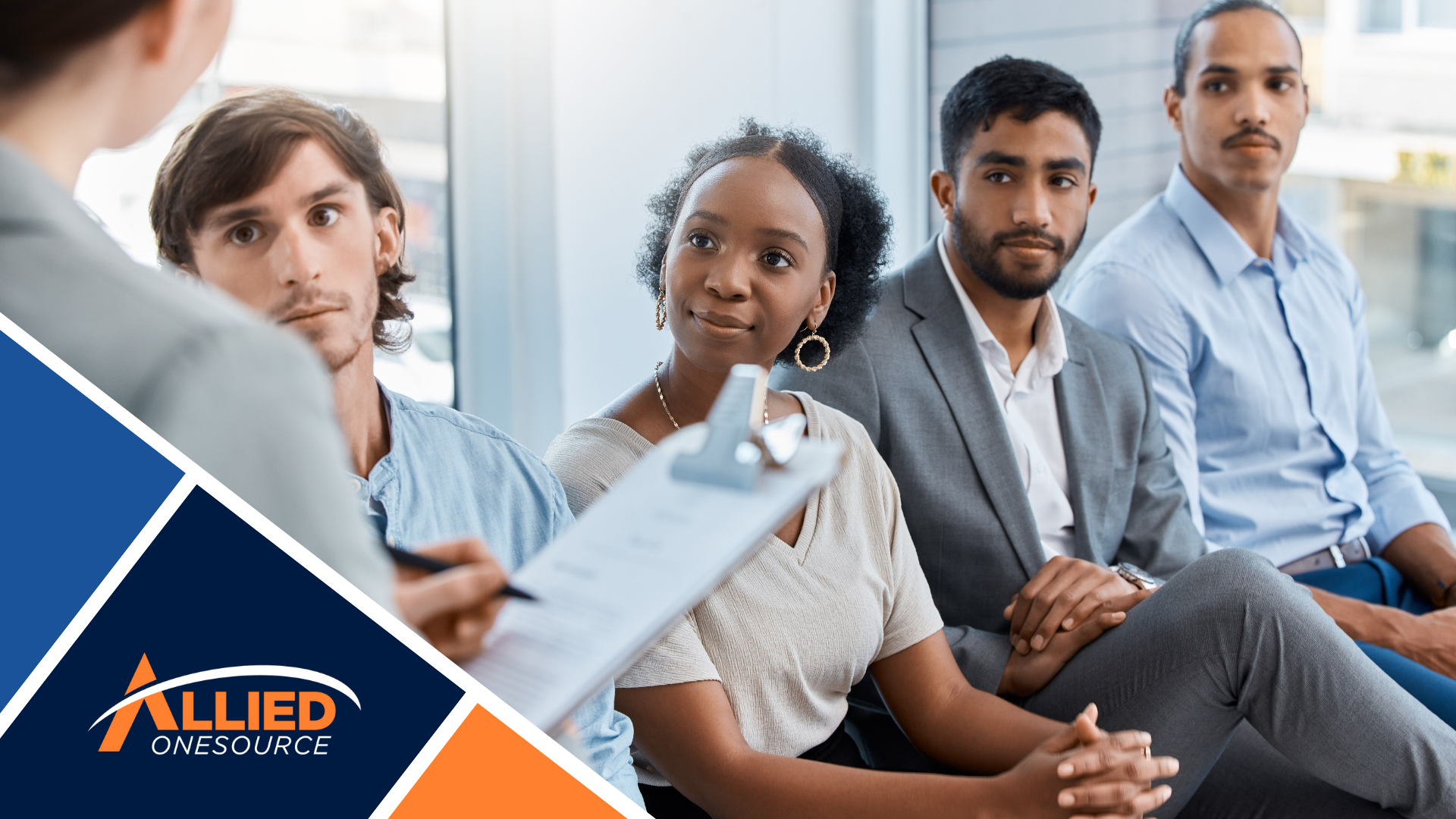 Four people sitting and listening to someone holding a clipboard.