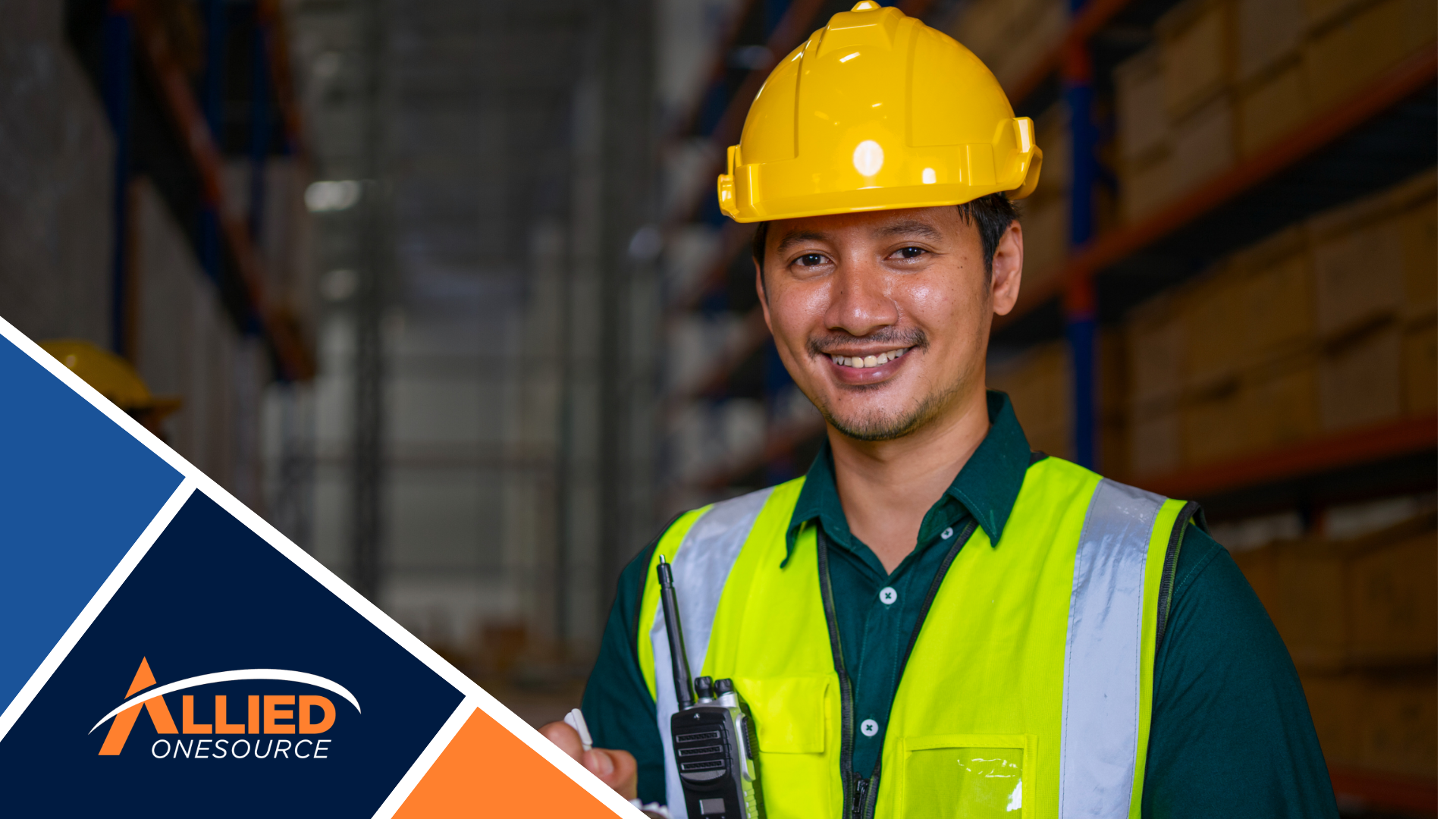 A smiling warehouse worker in a hard hat and safety vest represents light industrial safety standard