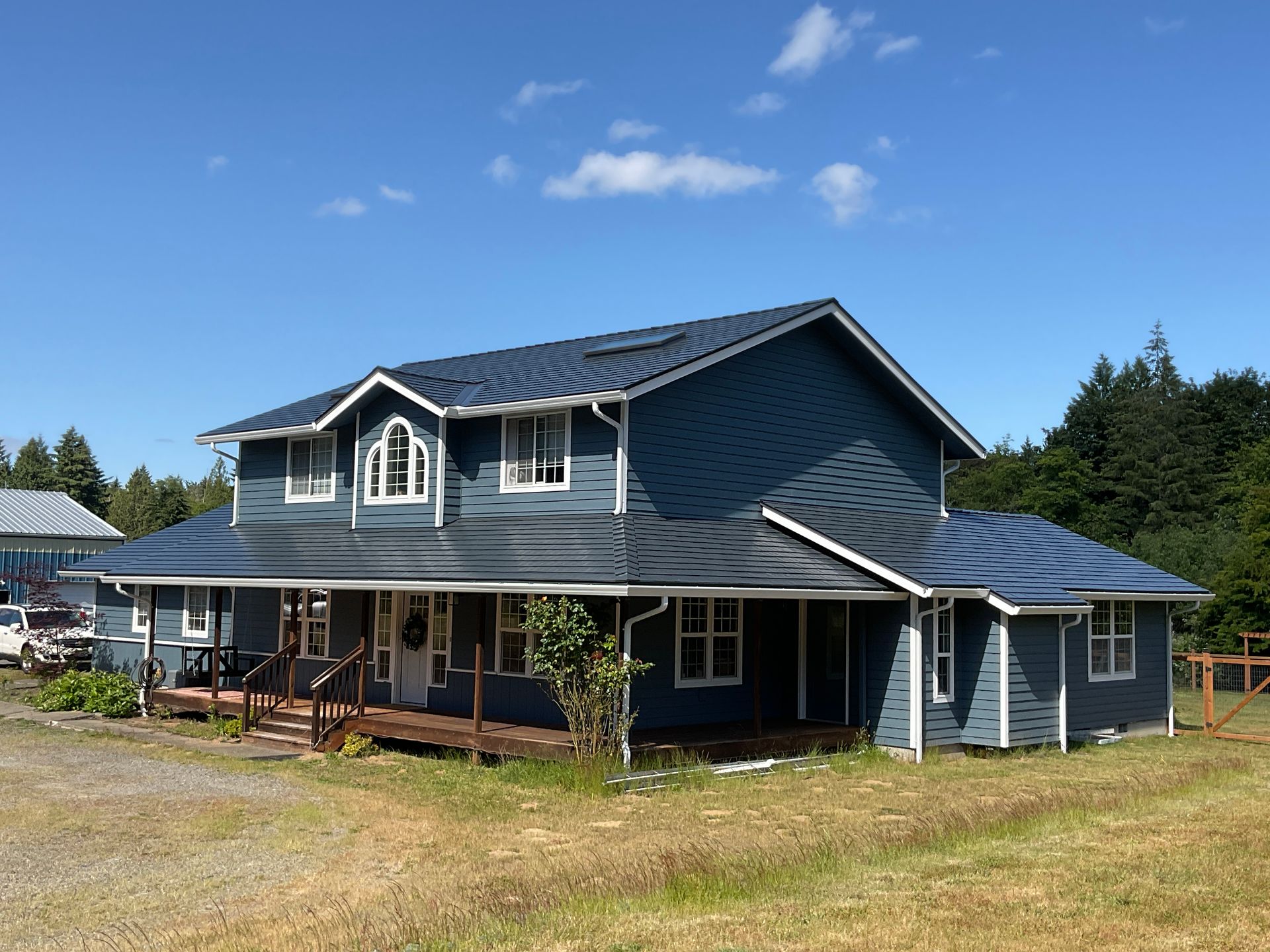 A large blue house with a porch and a blue sky in the background