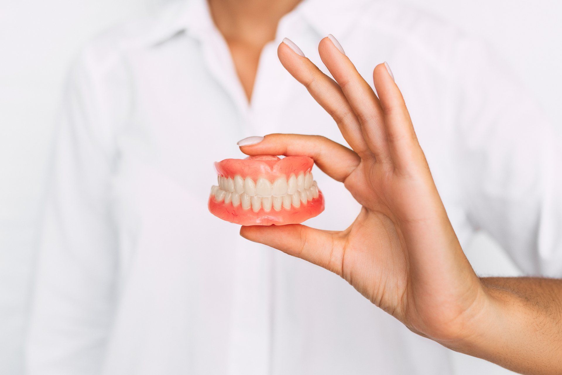 A woman is holding a denture in her hand.
