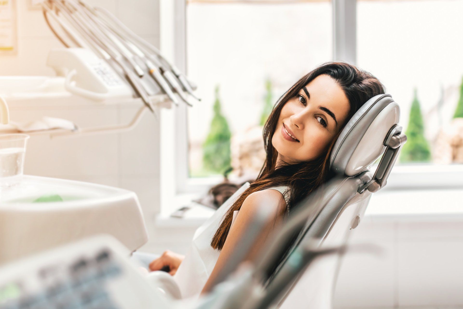 A woman is sitting in a dental chair and smiling.