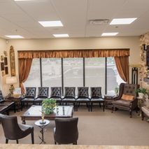 A waiting room with chairs , tables , and a fireplace.
