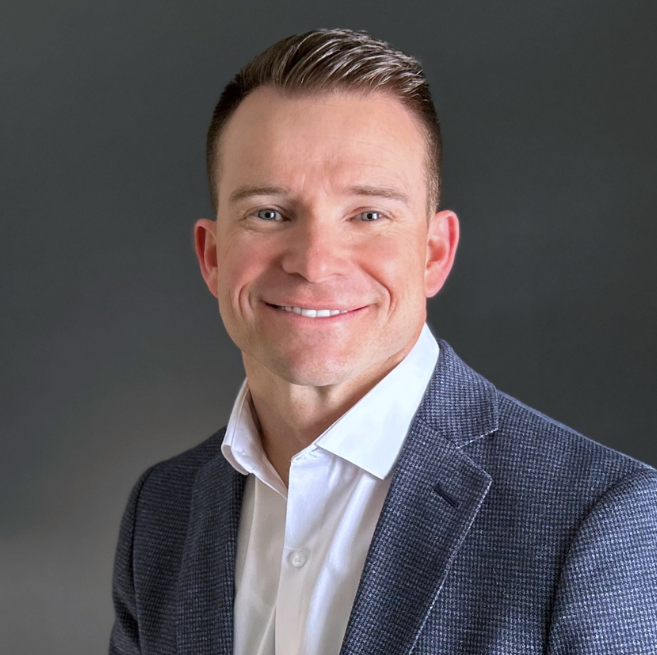 A man in a suit and white shirt is smiling for the camera.