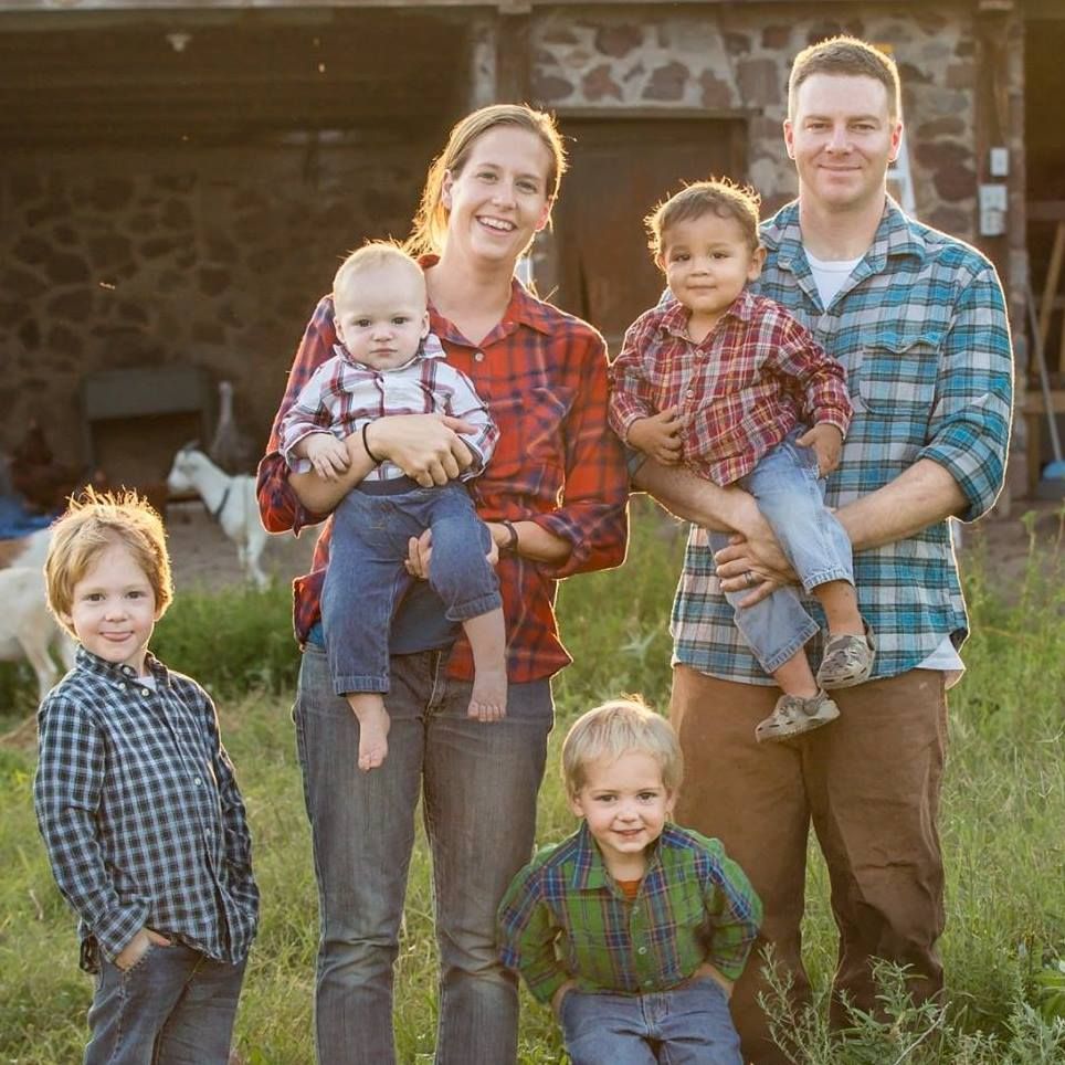 A family posing for a picture in a field with a goat in the background.