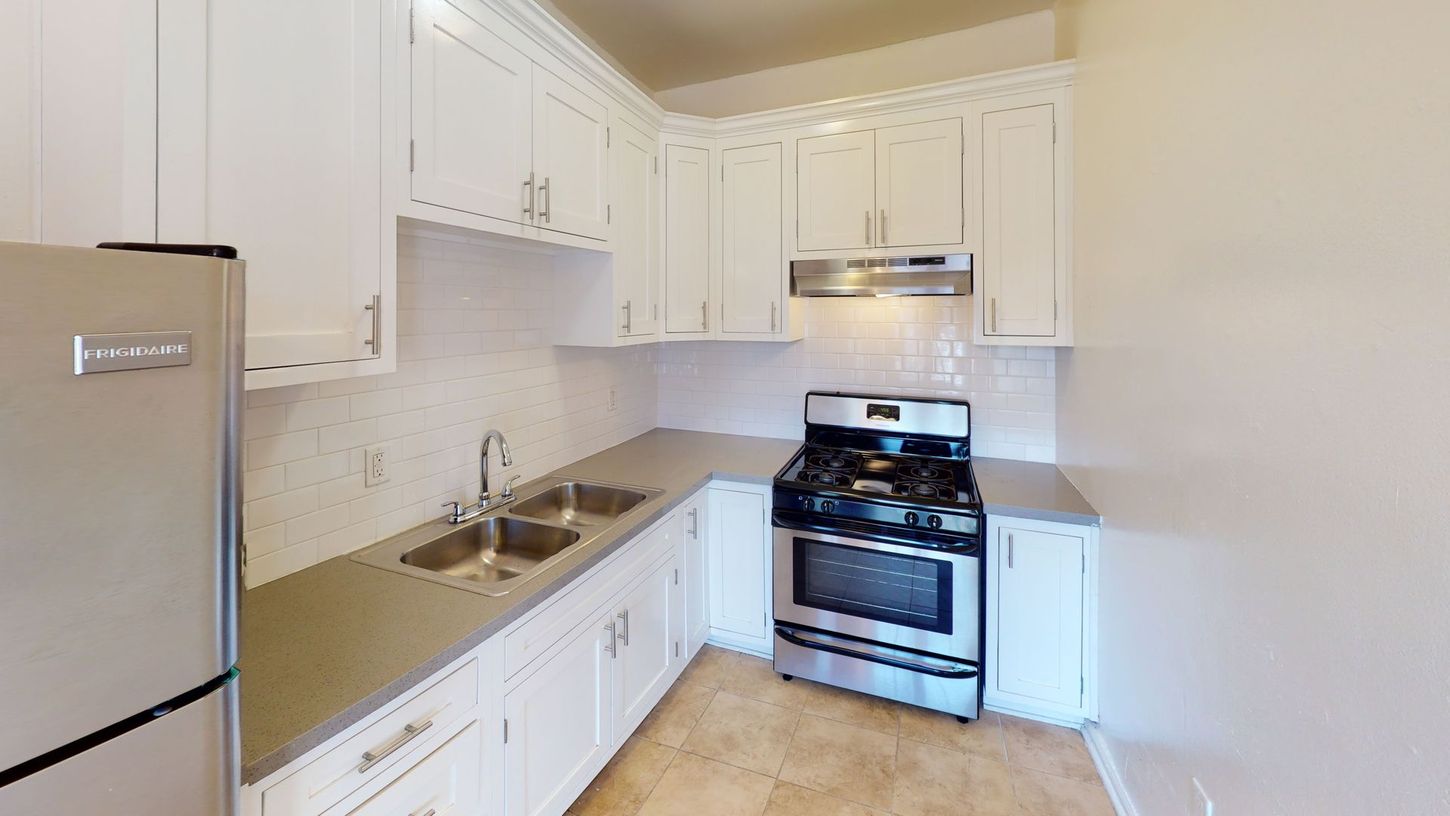White kitchen with stainless steel appliances and gray countertops.