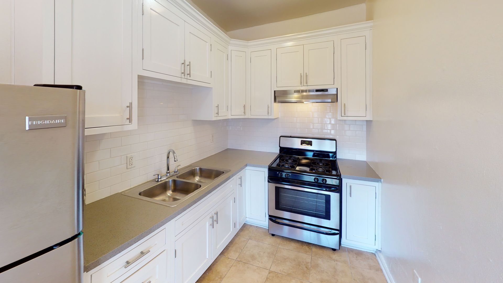 White kitchen with stainless steel appliances and gray countertops.