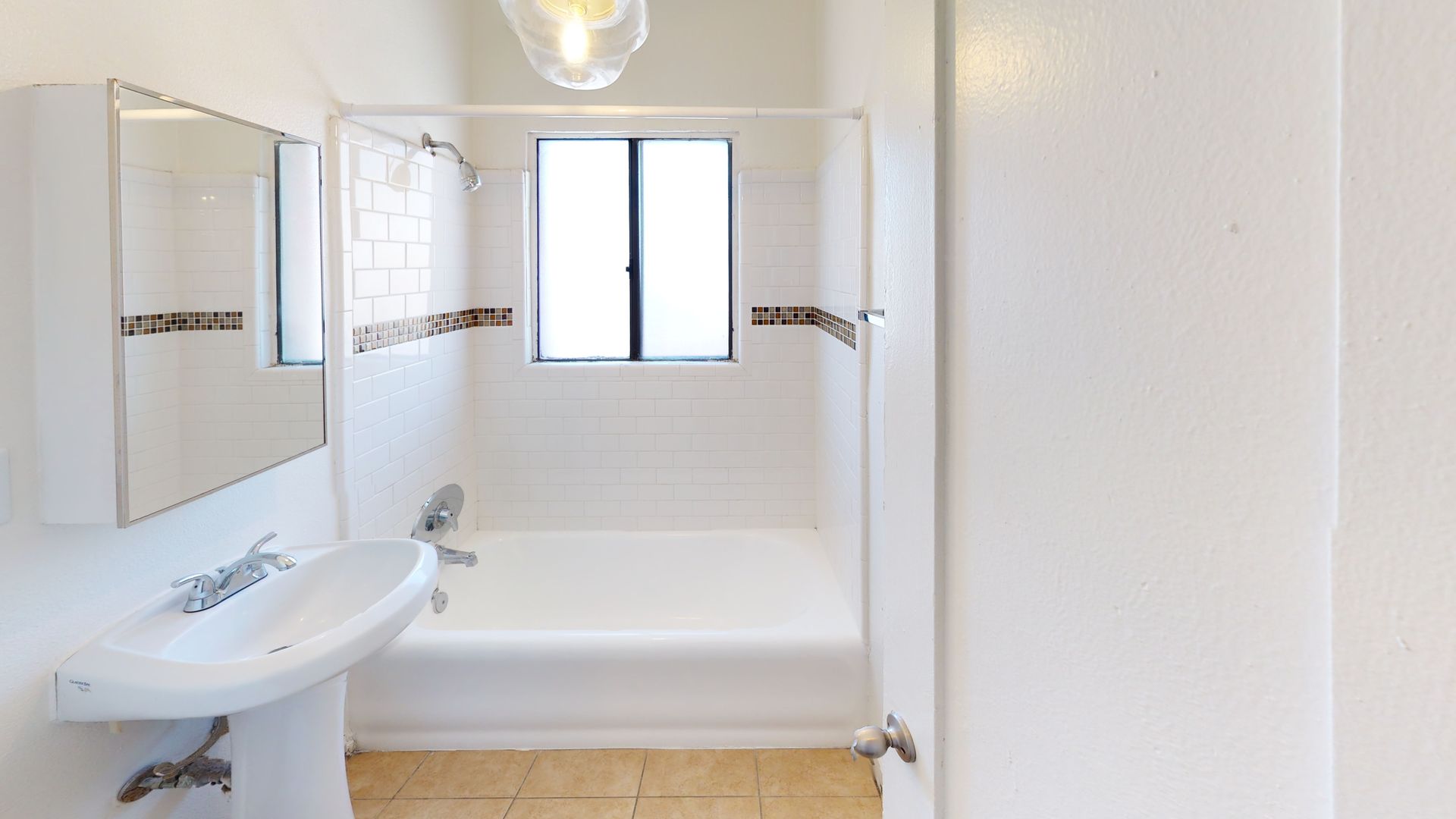 Bathroom with a white tub and sink, a window, and a light fixture.