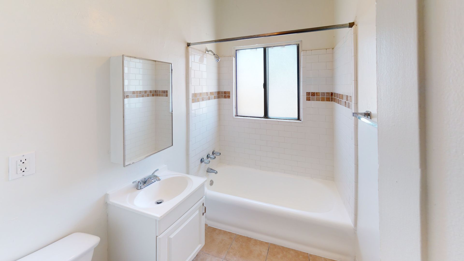 Bathroom with white fixtures, beige tile trim, and a window above the bathtub.