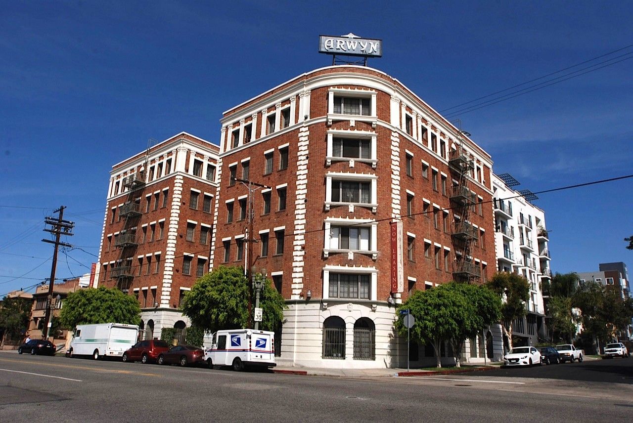 Brown brick building with white trim, arched windows on ground floor, and a rooftop sign reading 