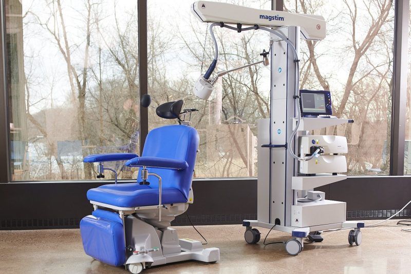 a magstim TMS machine sits next to a blue chair