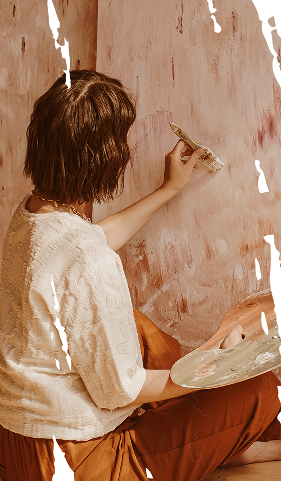 a woman is sitting on the floor painting a wall