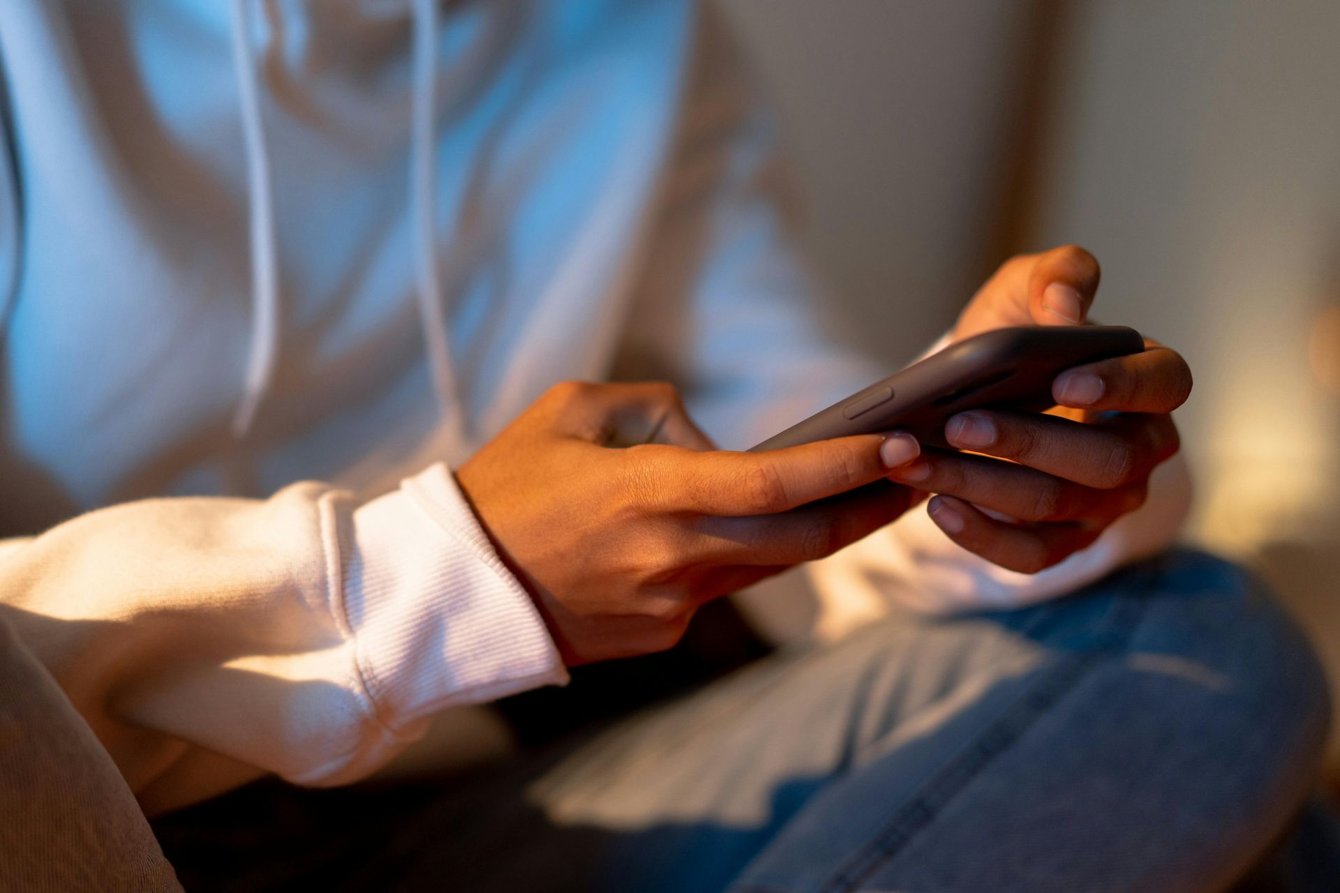 A person is sitting on a couch using a cell phone looking for help with depression.