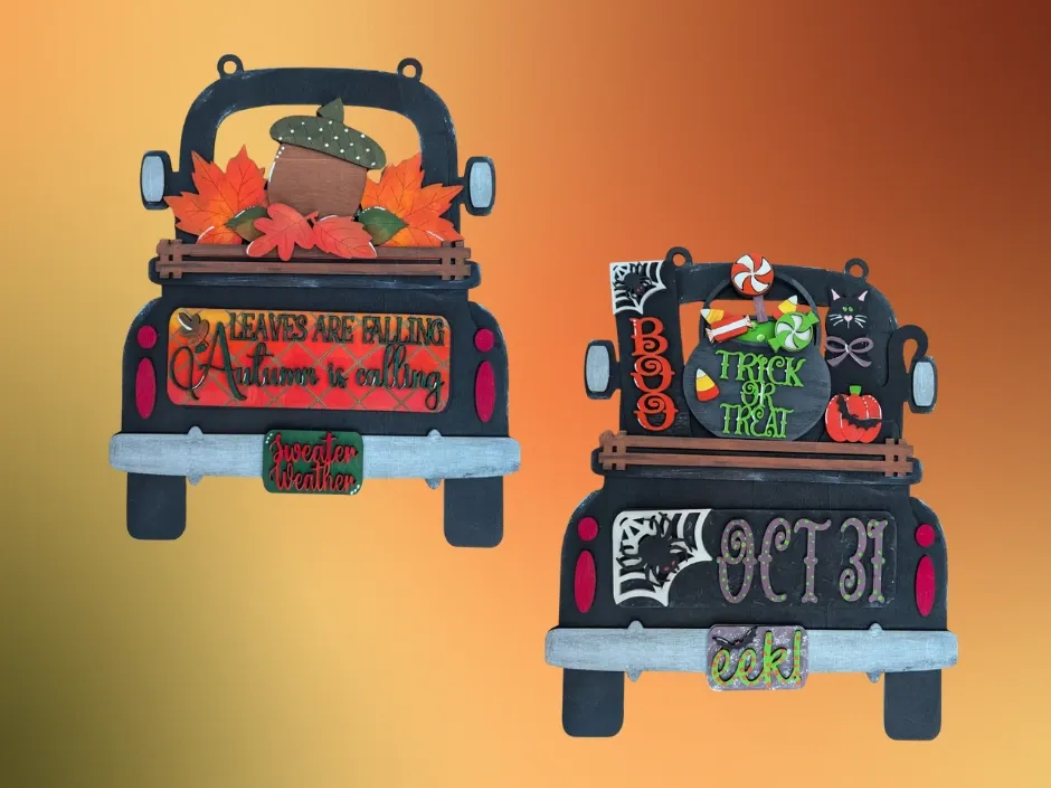 Two black truck-shaped Halloween decorations: one with fall leaves, the other with candy and a cauldron.