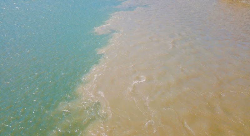 Blue and tan waters merge, showing a clear contrast and a visible mixing line.