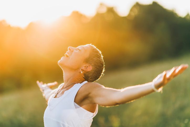 A woman is standing in a field with her arms outstretched.