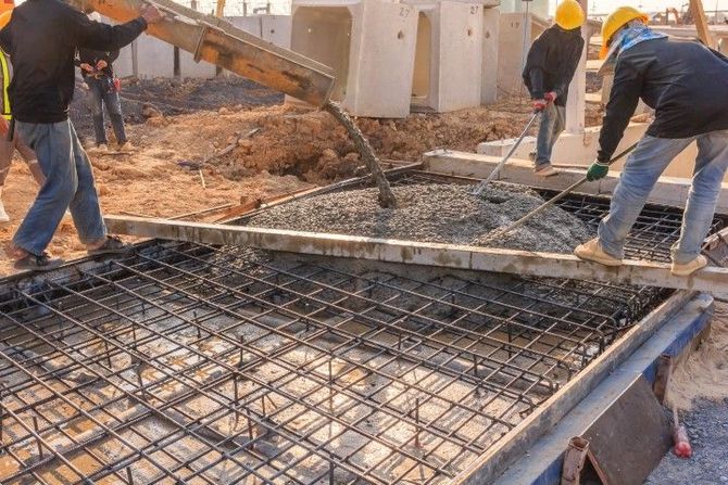 Workers pouring concrete over rebar at a construction site