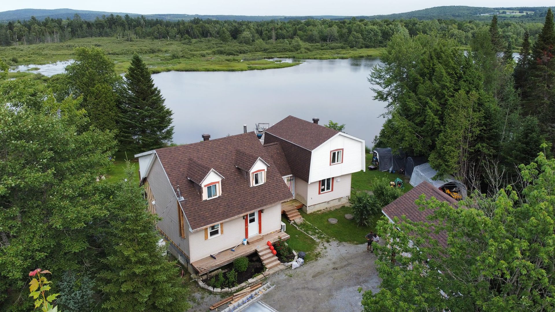 Une vue aérienne d'une maison à côté d'un lac entouré d'arbres.