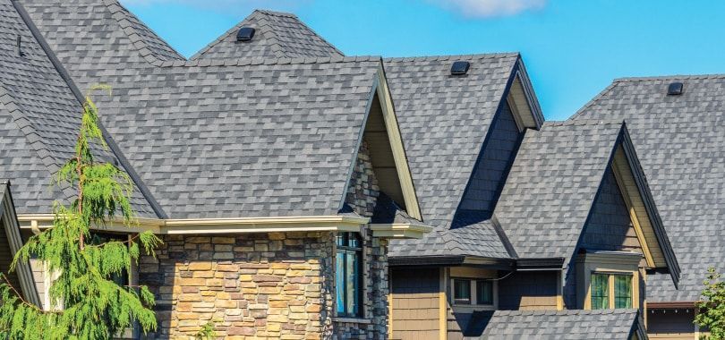 Une grande maison avec un toit gris et un mur en pierre.