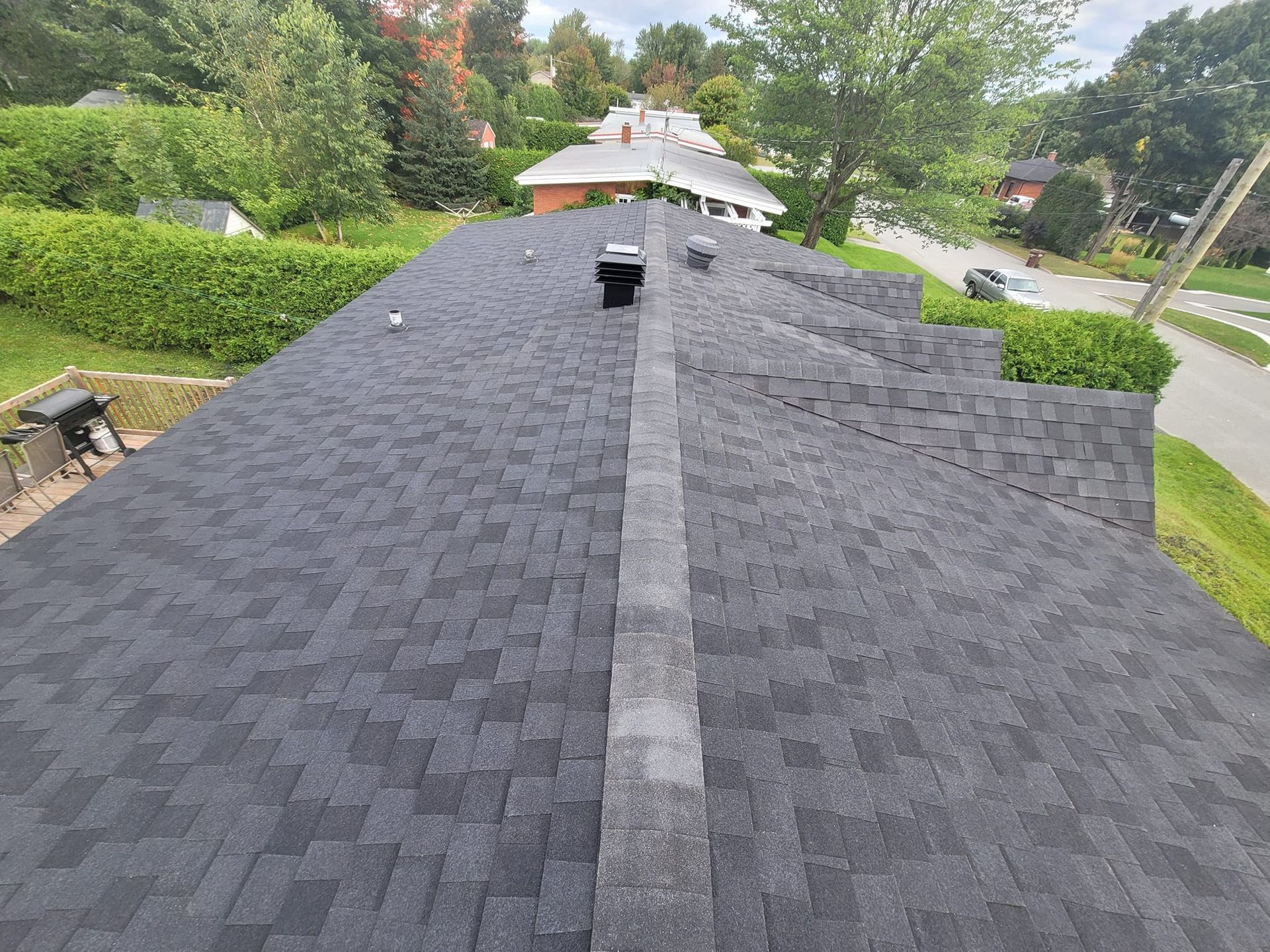 Un toit noir avec une cheminée dessus est en train d'être installé sur une maison.