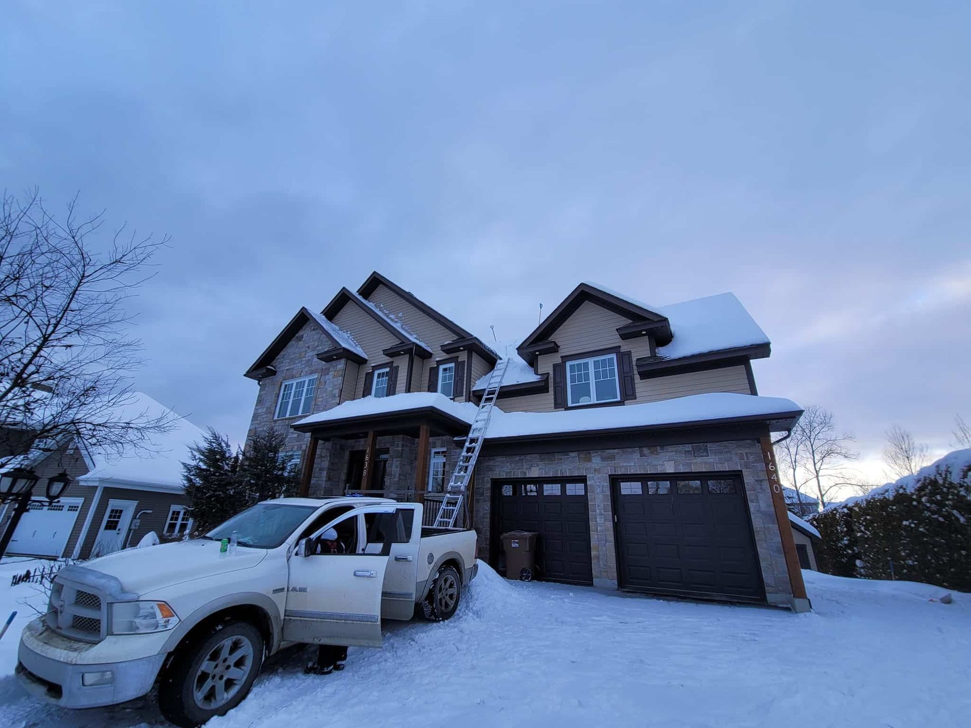 Un camion blanc est garé devant une maison couverte de neige.