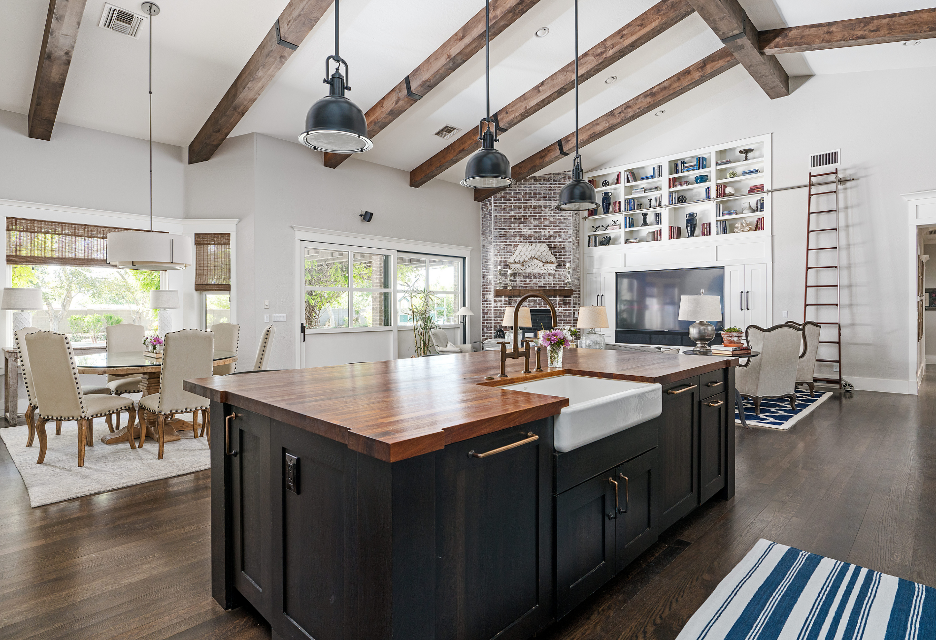 Kitchen with island, dining area, built-in shelving, high ceilings, and exposed wood beams.