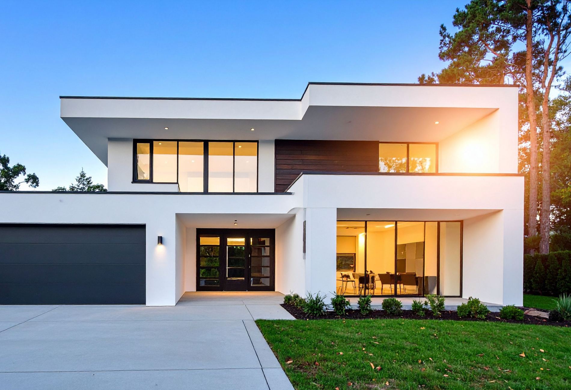 Modern white two-story house with black trim, glass windows, garage, and a green lawn.