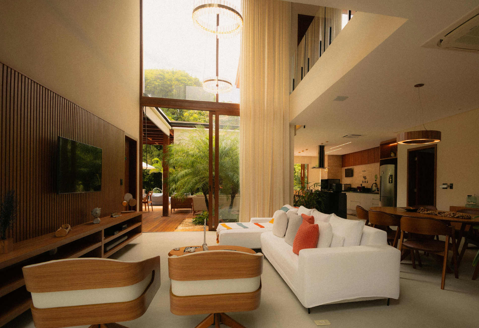 Spacious living room with white sofa, wood furniture, and large windows overlooking a patio.