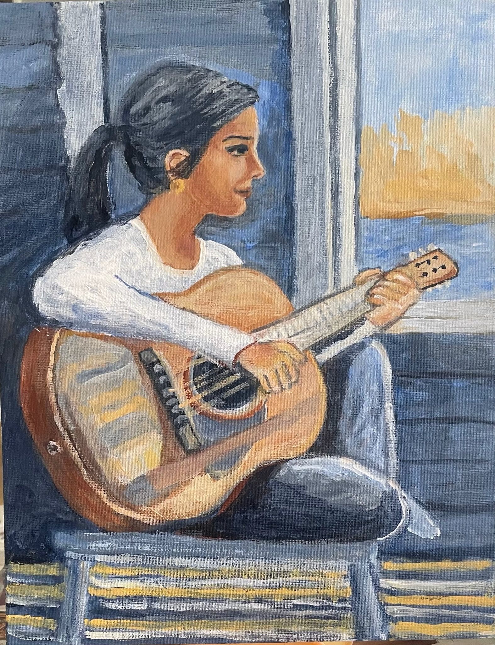 Person playing an acoustic guitar by a window, seated indoors with a city view outside.