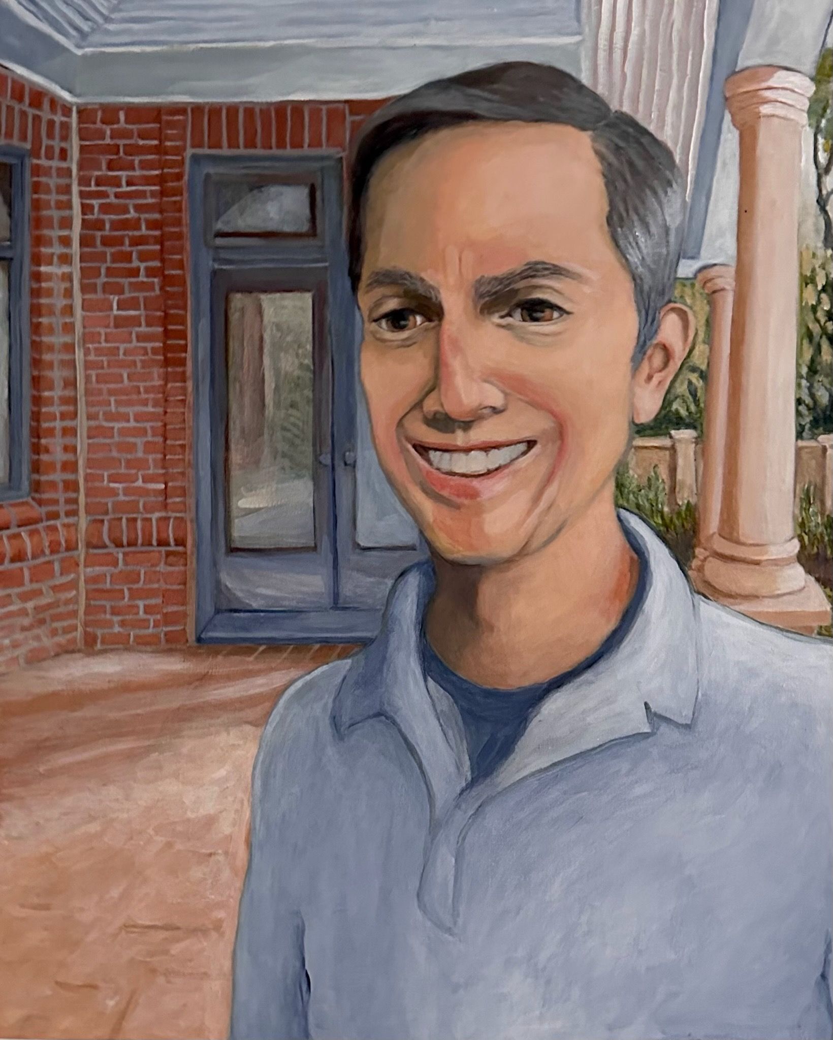 Smiling person in a light blue shirt standing outside a brick building with columns.