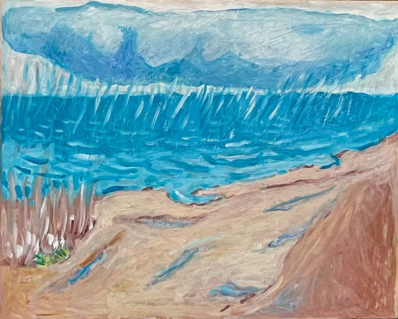 Stormy blue ocean with crashing waves beside a sandy shoreline and rocky beach.