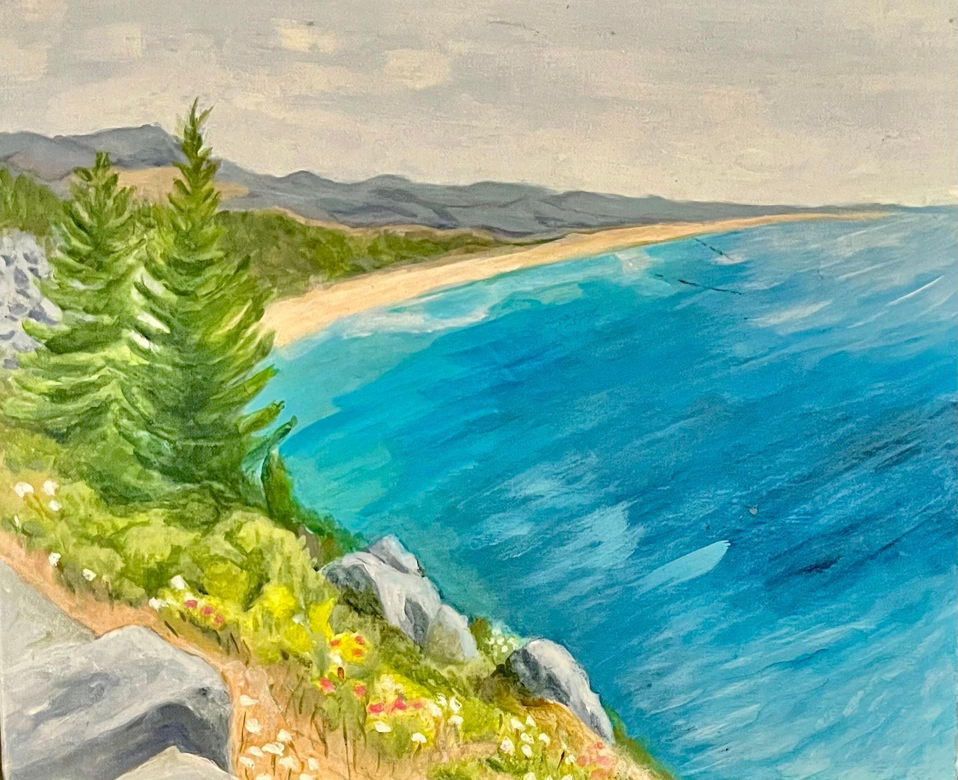 Small sailboat on blue water near a green, tree-lined shore with a sandy beach in the foreground.