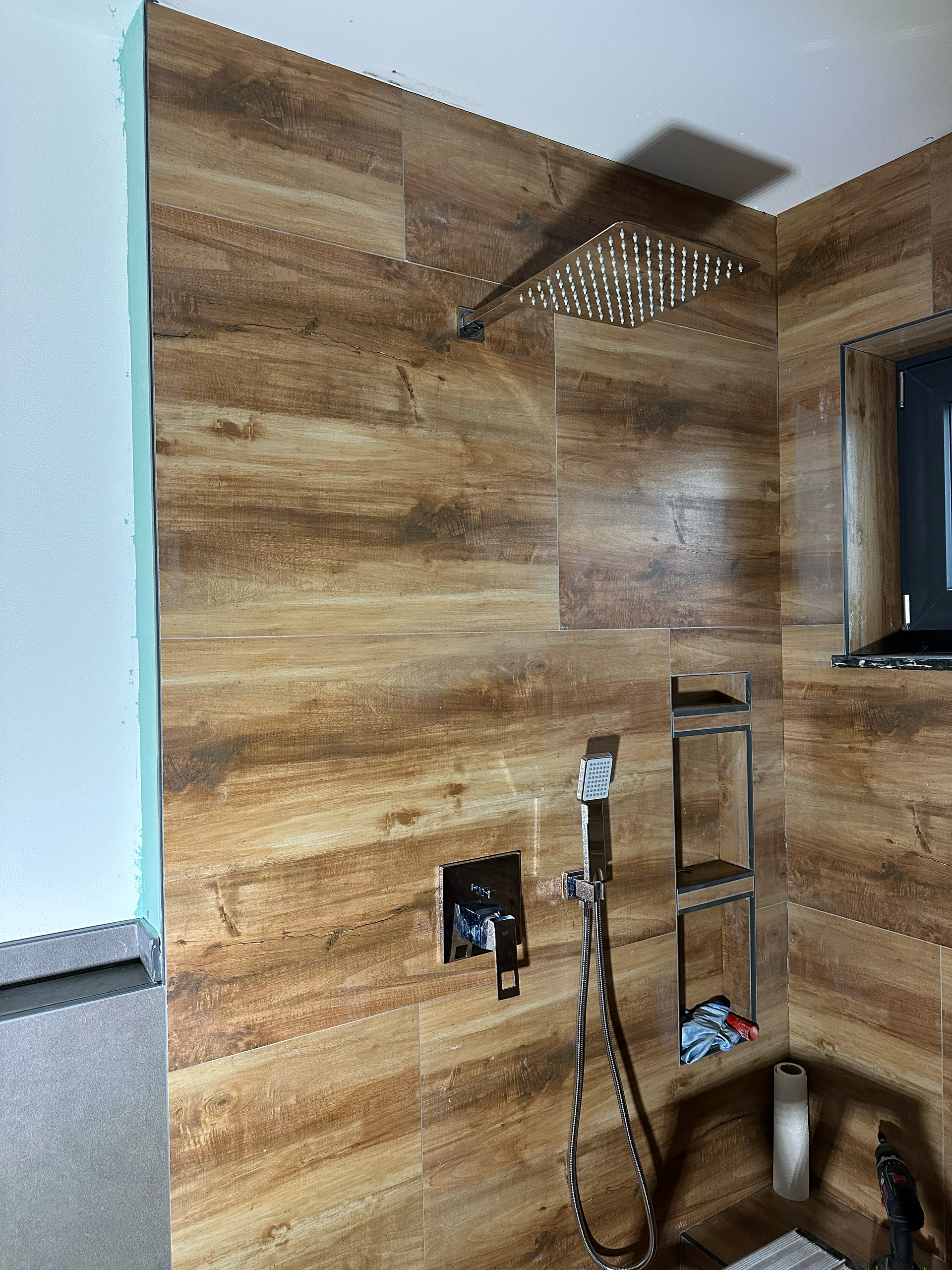 Ein Badezimmer mit Holzwand und Duschkopf.