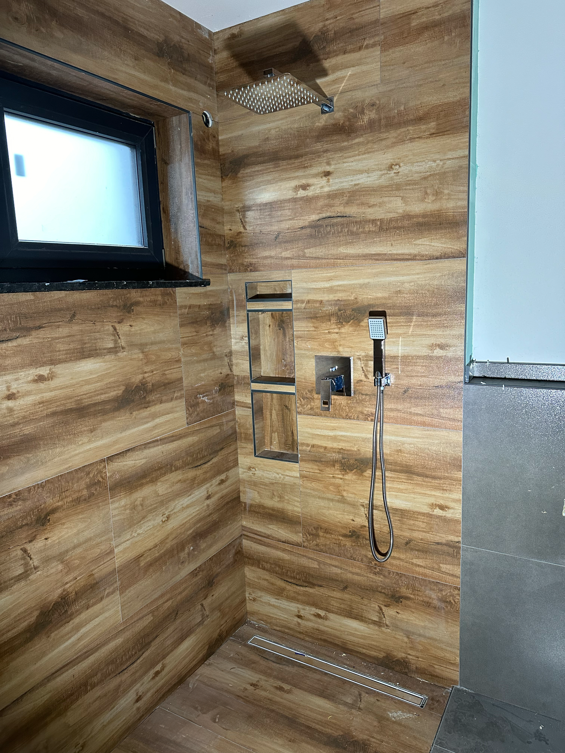 Ein Badezimmer mit Holzwänden und Duschkopf.