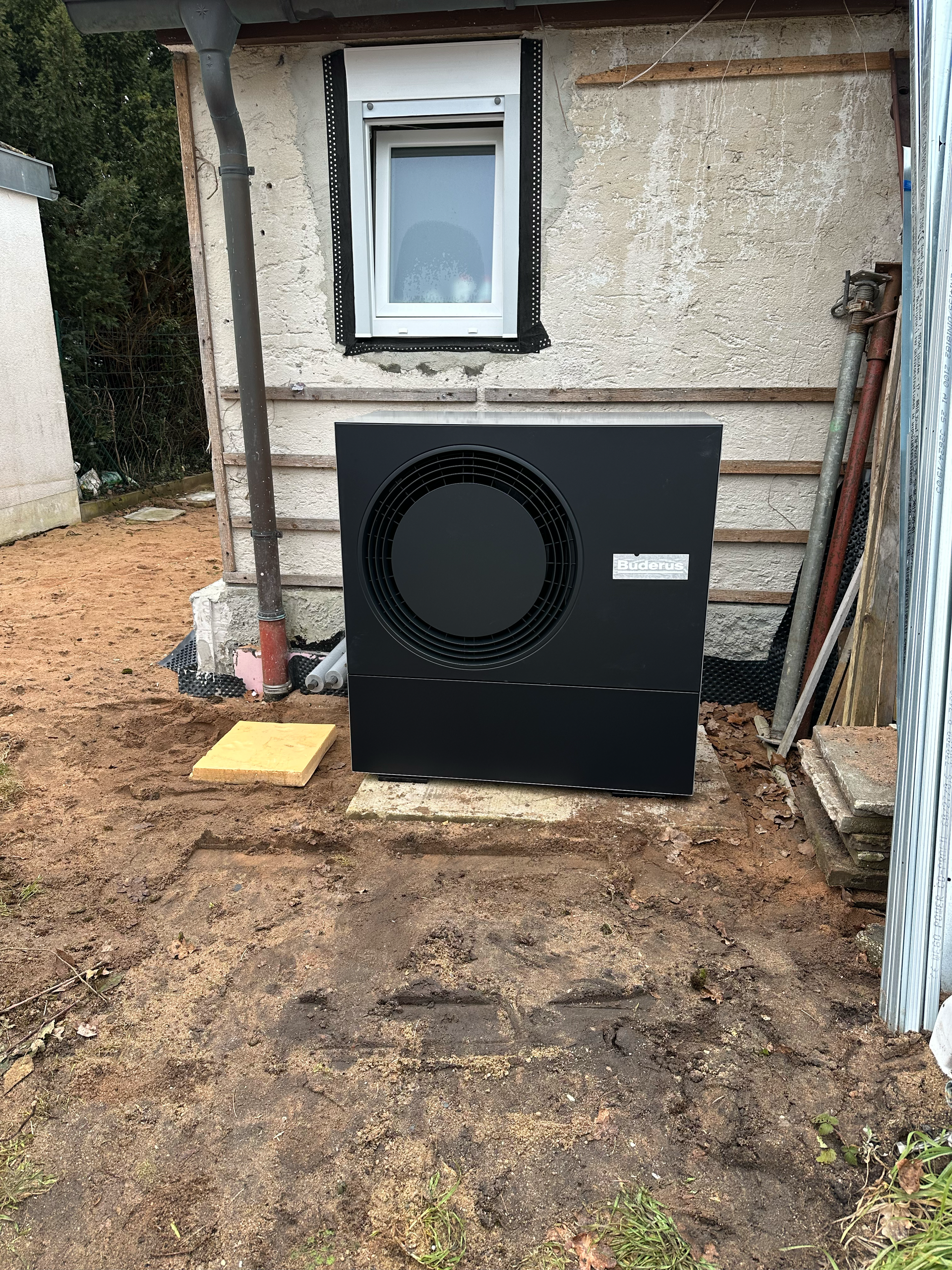 Vor einem Gebäude steht eine Wärmepumpe