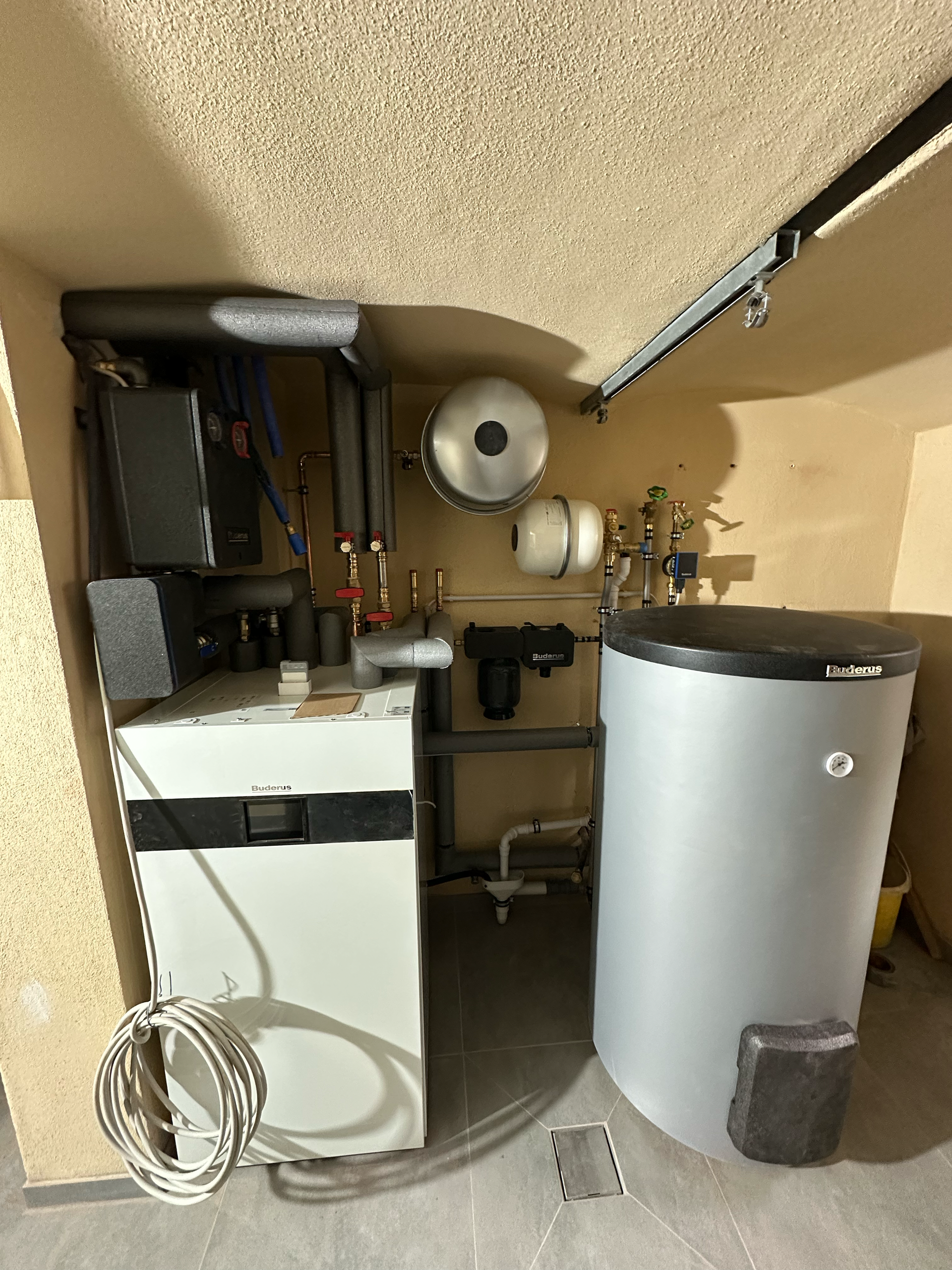 In einer Zimmerecke stehen ein Boiler und ein Warmwasserbereiter.