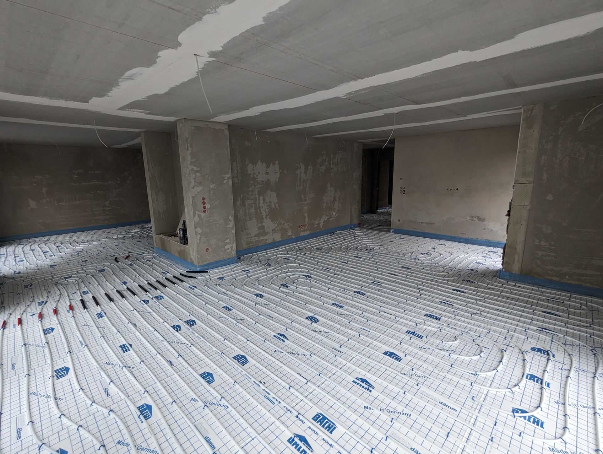 Ein Raum mit vielen leitungen für eine Fußbodenheizung auf dem Boden.