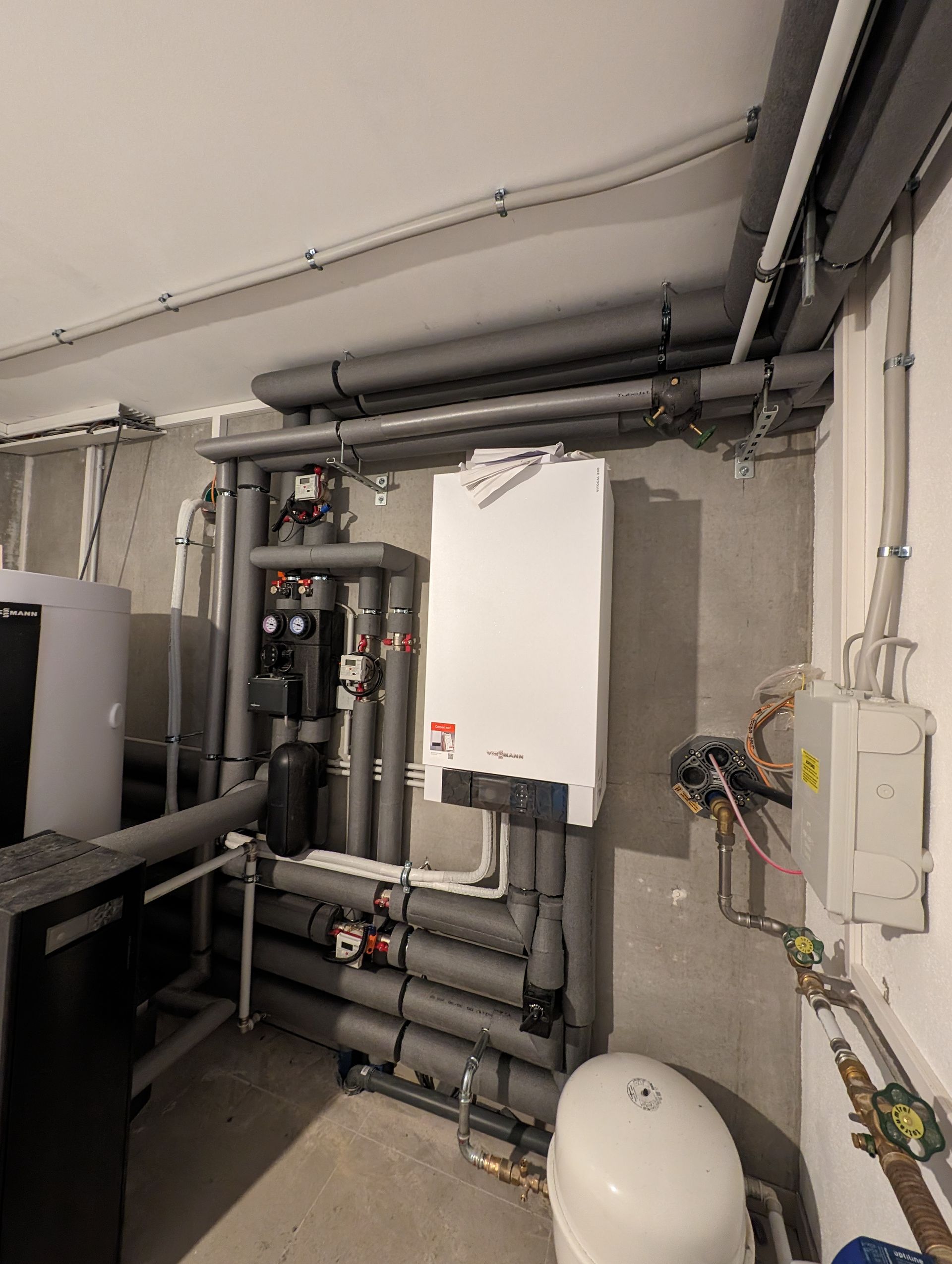 Ein Raum mit vielen Rohren und einem Boiler an der Wand.
