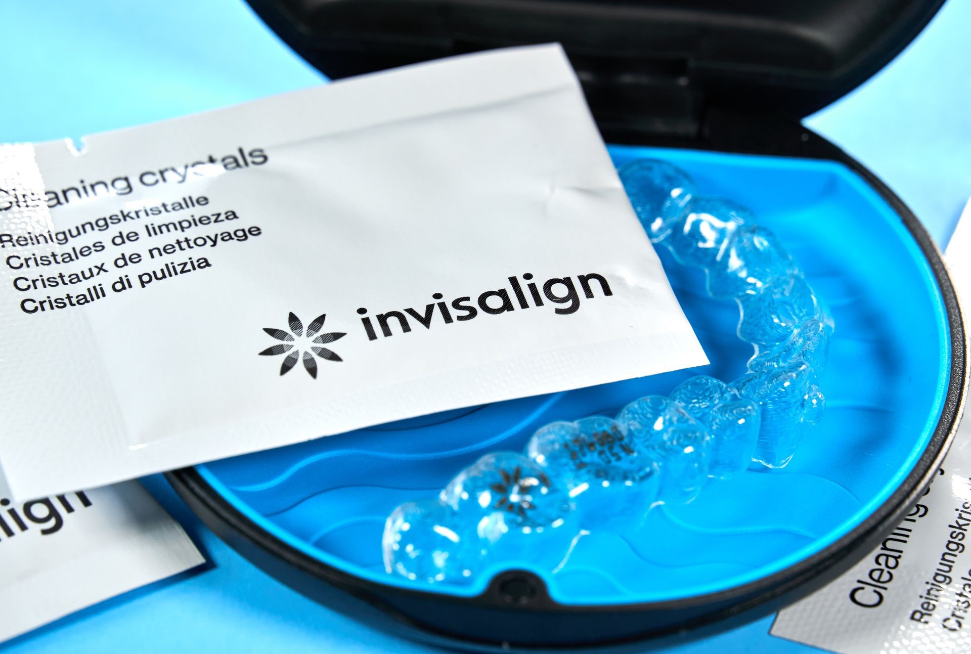 Invisalign aligner in a blue case, with cleaning crystals packet.