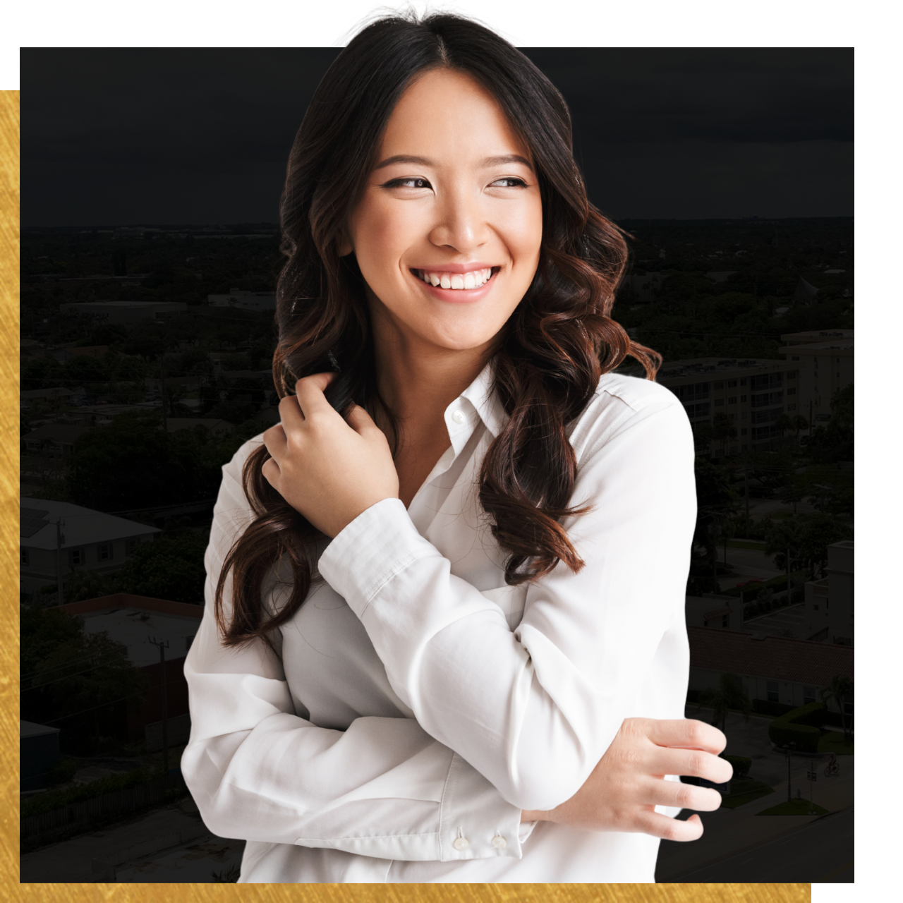 A woman in a white shirt is smiling with her arms crossed