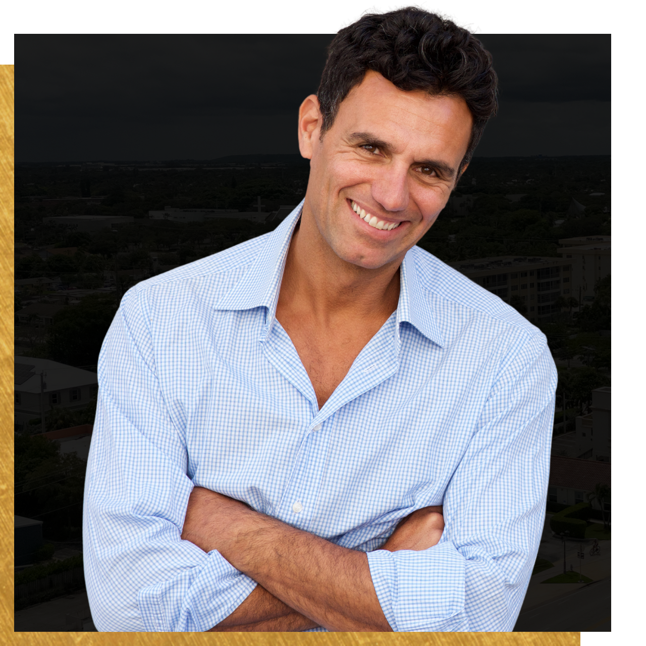 A man in a blue shirt is smiling with his arms crossed