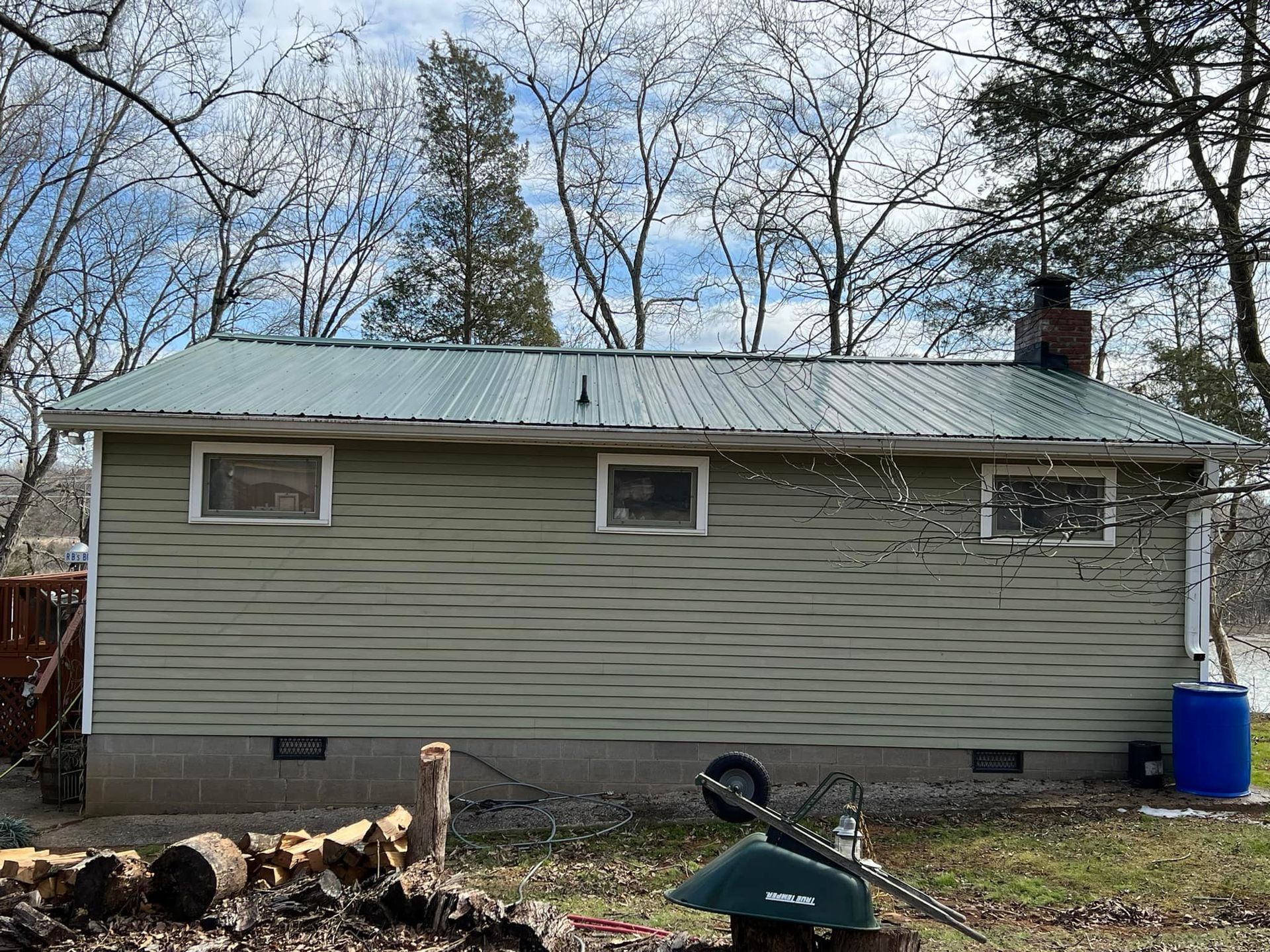 A house with a metal roof and a wheelbarrow in front of it.