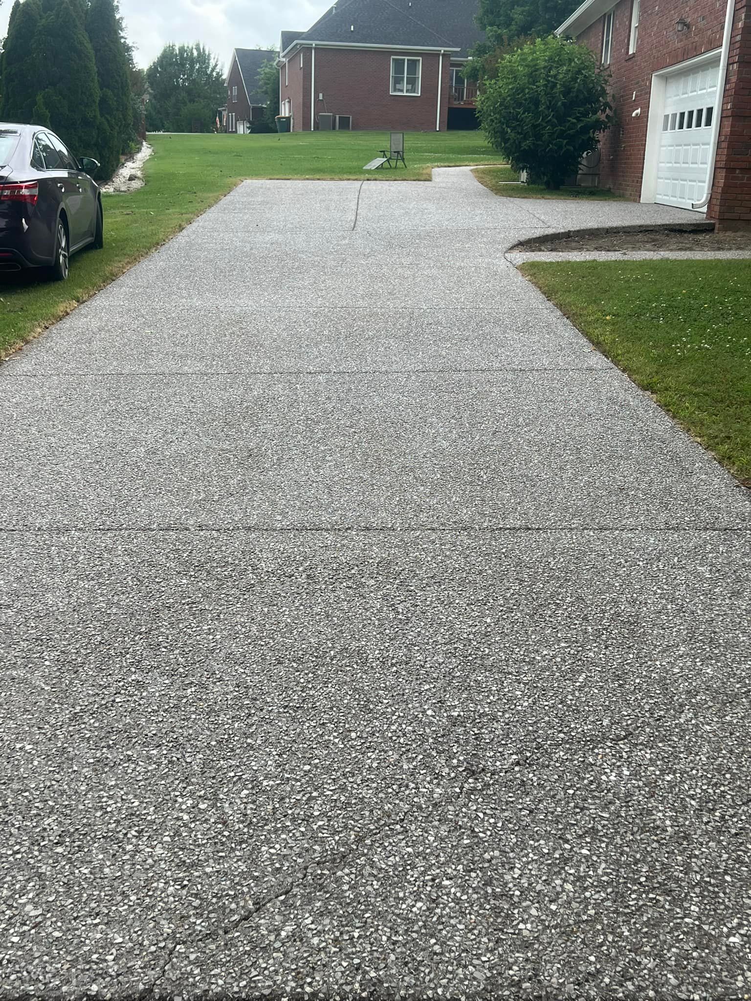 A car is parked on the side of a gravel driveway.