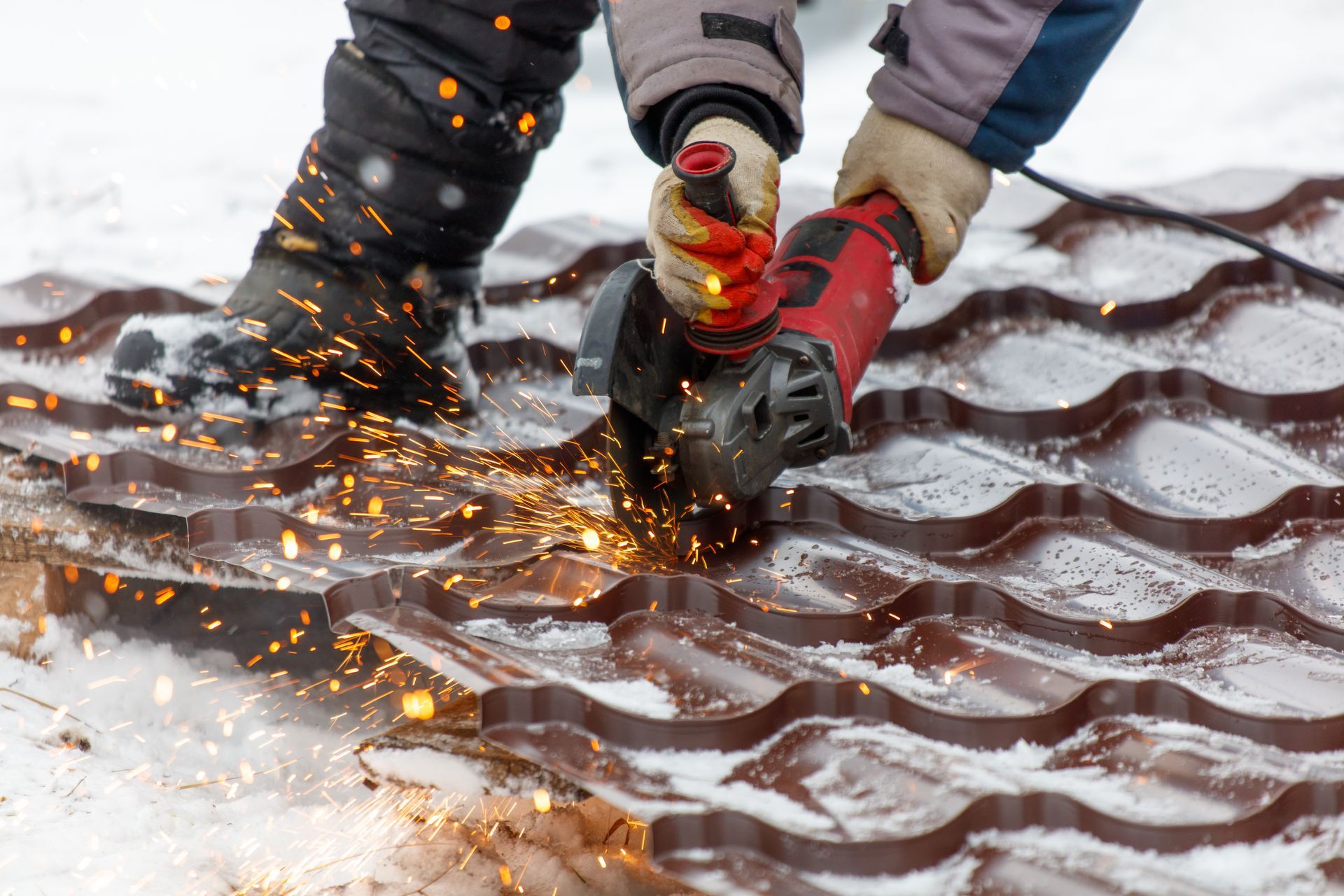 A labourer is cutting a roof with a power tool, showcasing bitumen cutting services. 