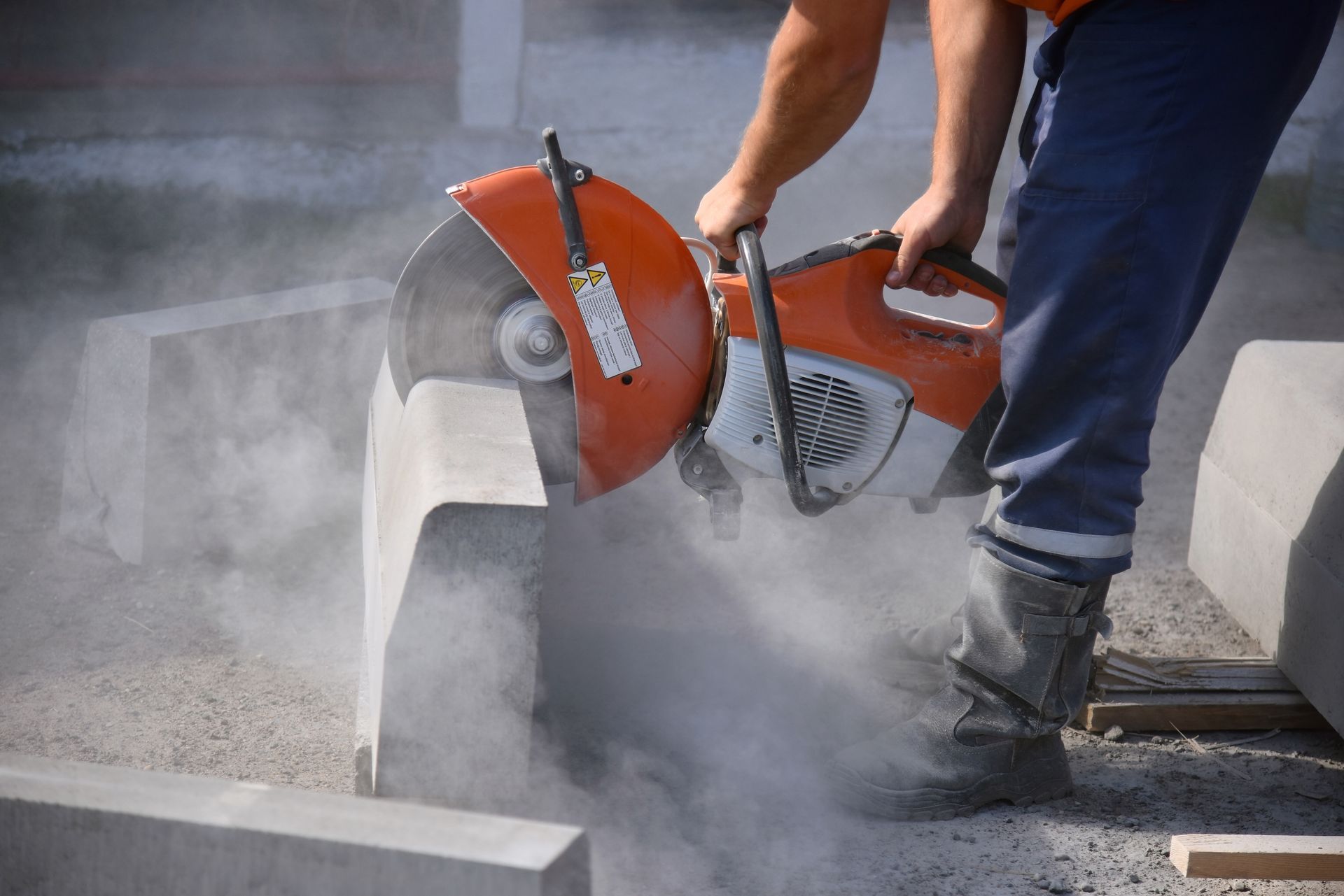 Close-up of a worker performing concrete cutting services, sawing a curb. 