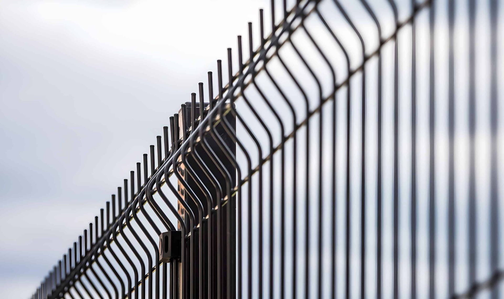 Black metal fence against a cloudy sky.