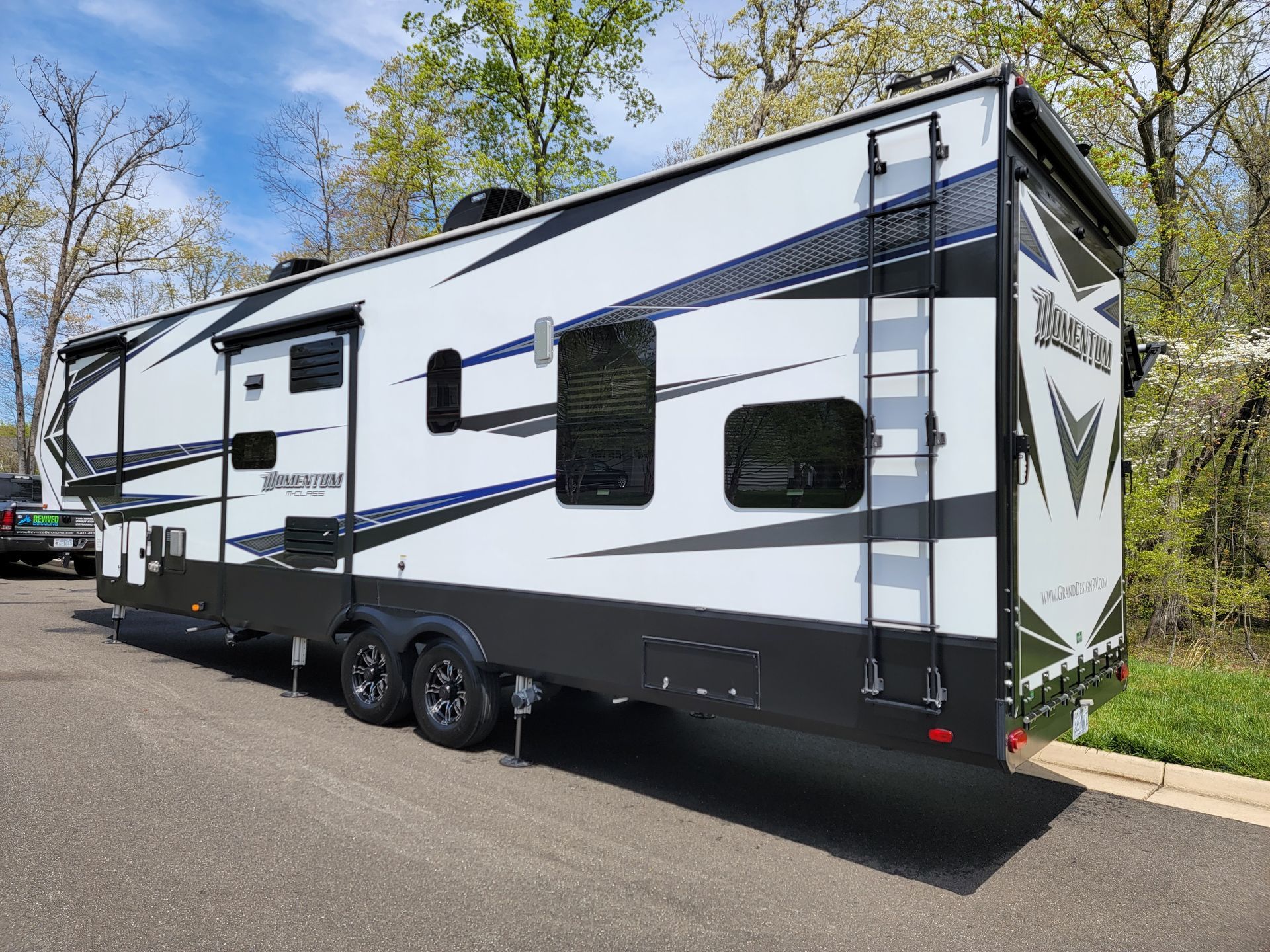A white and black trailer is parked on the side of the road.