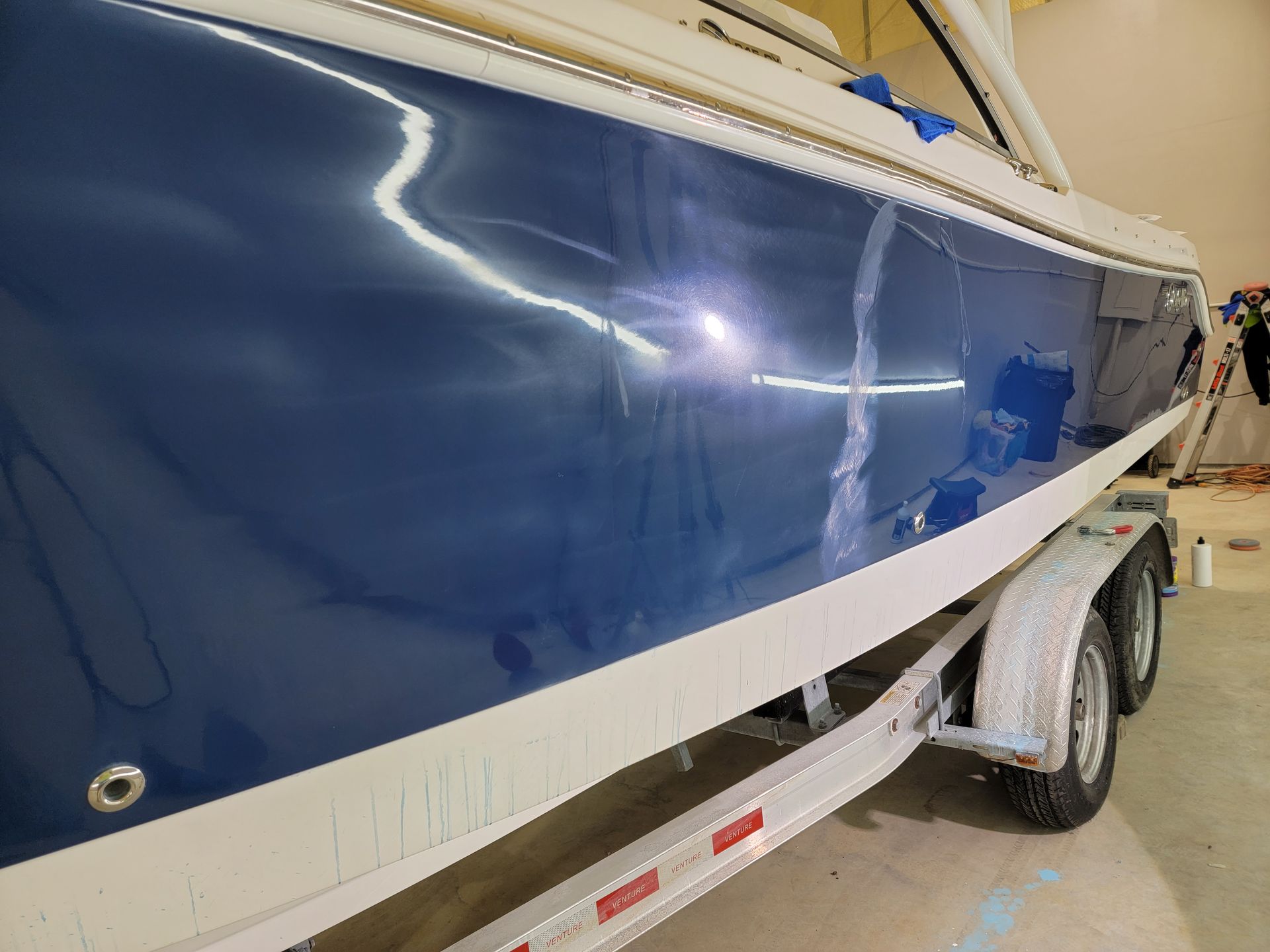 A blue boat is parked on a trailer in a garage.